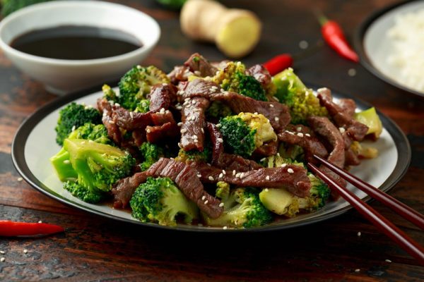 homemade beef and broccoli with rice and herbs on wooden table